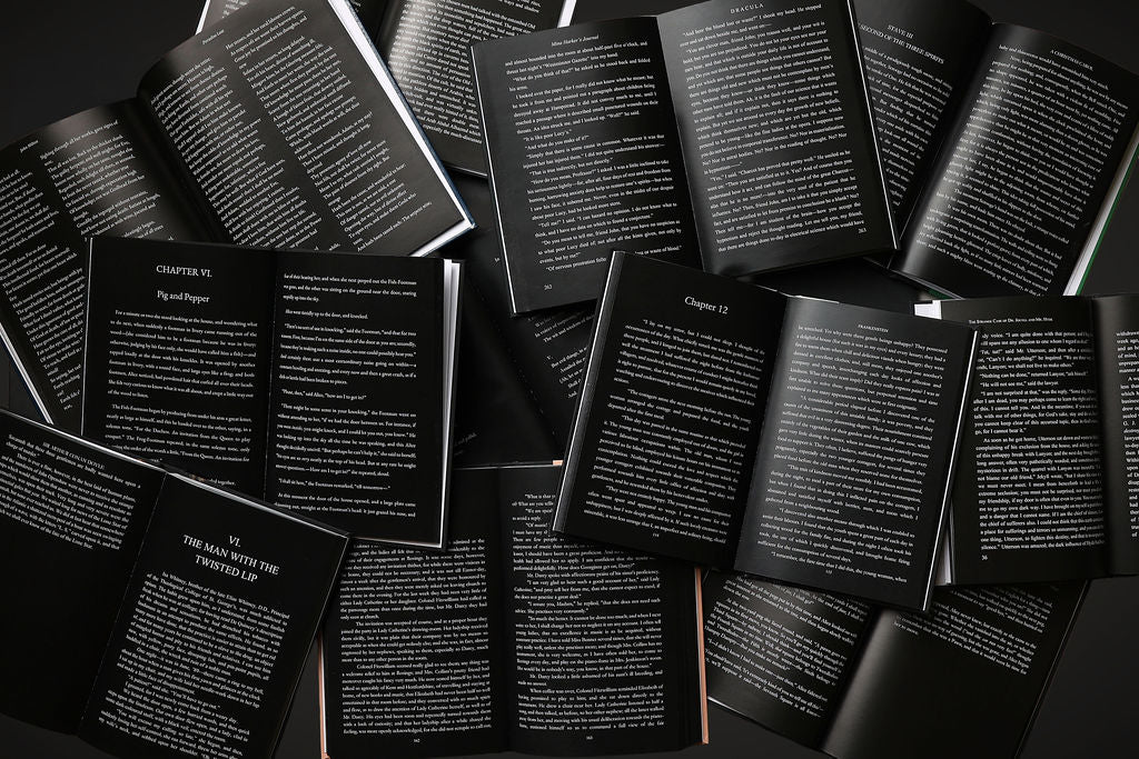 Multiple books with black pages and white text stacked on top of each other