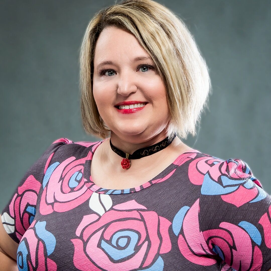 Woman wearing a dress with pink and blue floral pattern against a gray background
